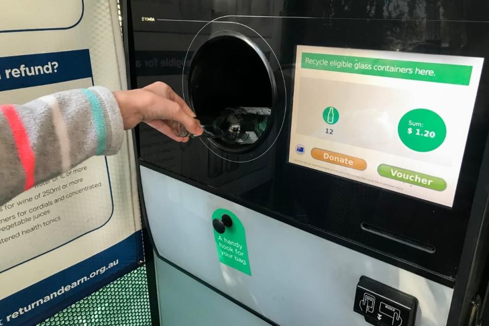 Person recycling bottle into the Return and Earn machine