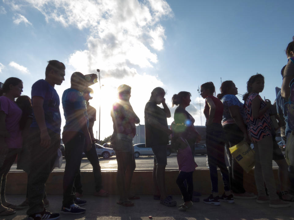 FILE - Migrants seeking asylum wait in line with their case paperwork during a weekly trip by volunteers, lawyers, paralegals and interpreters to the migrant campsite outside El Puente Nuevo in Matamoros, Mexico, Saturday, Oct. 5, 2019. A federal judge on Monday, Aug. 31, 2020, blocked U.S. Customs and Border Protection employees from conducting the initial screening for people seeking asylum, dealing a setback to one of the Trump administration's efforts to rein in asylum. (Denise Cathey/The Brownsville Herald via AP, File)