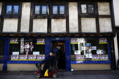 A woman drives her mobility scooter past the United Kingdom Independence Party (UKIP) campaign office for the by-election in Rochester, in southeastern England, November 11, 2014. REUTERS/Andrew Winning