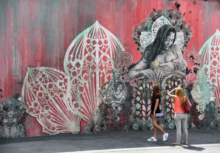 People look at a mural by US artist Swoon in the Wynwood neighborhood of Miami, Florida, on September 28, 2016