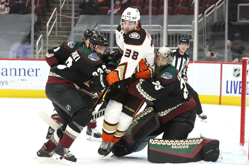 Anaheim Ducks center Derek Grant (38) gets tangled up with Arizona Coyotes defenseman Jakob Chychrun (6), defenseman Alex Goligoski (33), and goaltender Darcy Kuemper (35) in the first period during an NHL hockey game, Tuesday, Jan. 26, 2021, in Glendale, Ariz. (AP Photo/Rick Scuteri)