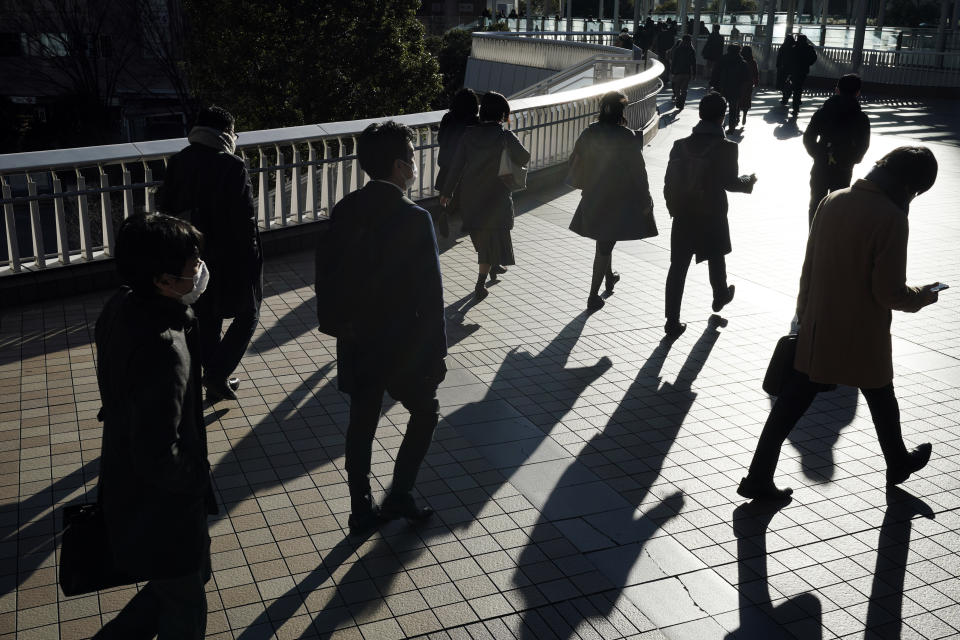 Commuters wearing face mask make their way during a rush hour Friday, Jan. 8, 2021 in Tokyo. Japanese Prime Minister Yoshihide Suga declared a state of emergency Thursday for Tokyo and three other prefectures to ramp up defenses against the spread of the coronavirus. (AP Photo/Eugene Hoshiko)