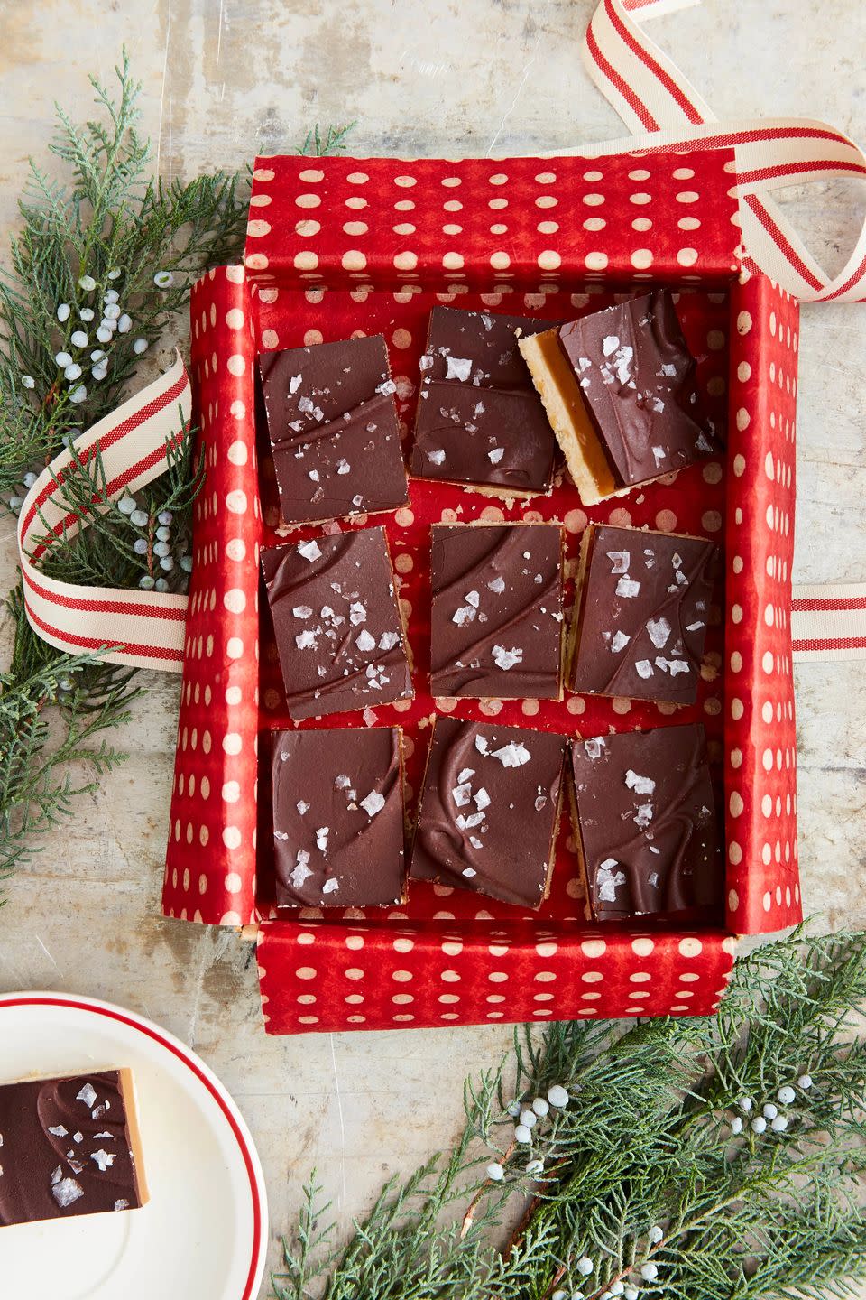 millionaires shortbread bars cut into squares in a tin lined with tissue paper