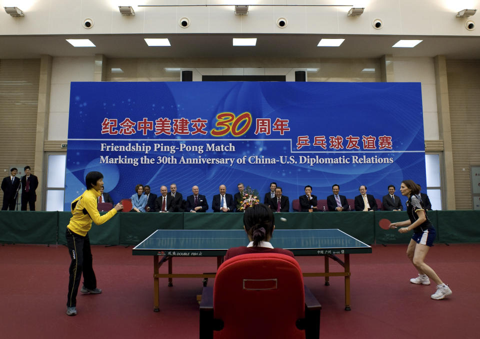 FILE - U.S. Deputy Secretary of State John Negroponte, center left, and China Vice Foreign Minister Wang Guangya, center right, watch a game during a commemorative table tennis match marking China's invitation to a U.S. table tennis team to visit in 1971, known as "ping-pong diplomacy," in Beijing, China, in this Wednesday, Jan. 7, 2009, file photo. Playing at left is Qi Baoxiang of China, and at right Judy Bochenski Hoarfrost from the U.S., a member of the 1971 U.S. table tennis team. (AP Photo/Andy Wong, Pool, File)