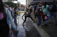 A woman protects her shoes with plastic bags as she wades through a street inundated by heavy rains, in Caracas, Venezuela, Wednesday, June 29, 2022. Forecasters issued a hurricane watch for the Nicaragua-Costa Rica border as a tropical disturbance sped over the southern Caribbean on a path toward Central America. Venezuela shuttered schools, opened shelters and restricted air and water transportation on Wednesday as President Nicolas Maduro noted that the South American country already has been struggling with recent heavy rains. (AP Photo/Ariana Cubillos)