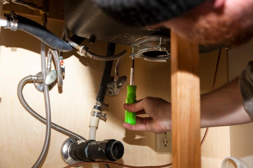 Man tightening screws around garbage disposal mounting ring.