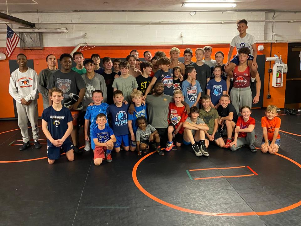 Youth wrestlers pose with Paniro Johnson (center, kneeling) after a practice held by Rambler Wrestling Club ON Tuesday at Cathedral Prep.