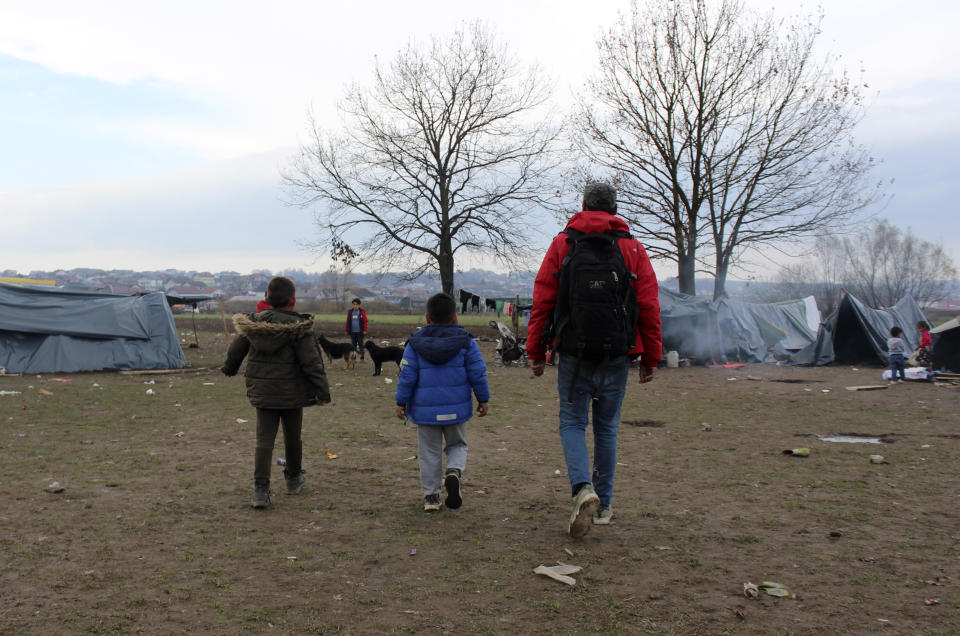 Ibrahim Rasool, Afghan refugee, formerly a FIFA-licensed futsal referee, right, walks with children at a makeshift camp housing migrants, in Velika Kladusa, Bosnia, Saturday, Nov. 13, 2021. Ibrahim Rasool loved his job as a futsal referee because of sportsmanship and fair play. But the 33-year-old man from Afghanistan says there is nothing fair about the way the European Union treats people seeking refuge from violence and war. (AP Photo/Edvin Zulic)