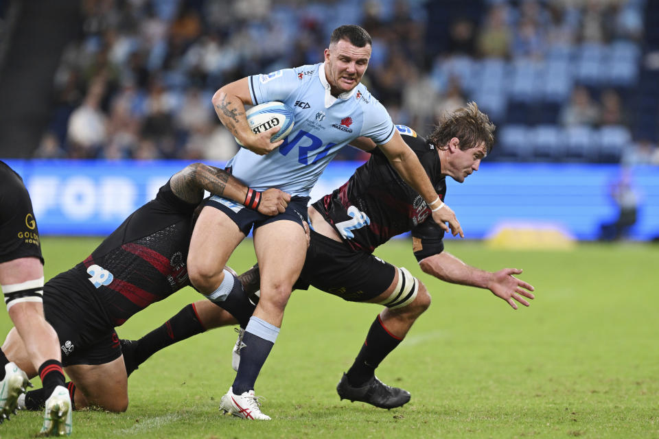 Dylan Pietsch of the Waratahs, center, attempts to break the tackle of Crusaders players during their Super Rugby Pacific Round 8 match in Sydney, Friday, April 12, 2024. (Dean Lewins/AAP Image via AP)