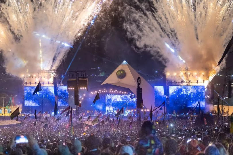 Fireworks illuminate the night sky as  crowds gather at the main Pyramid Stage