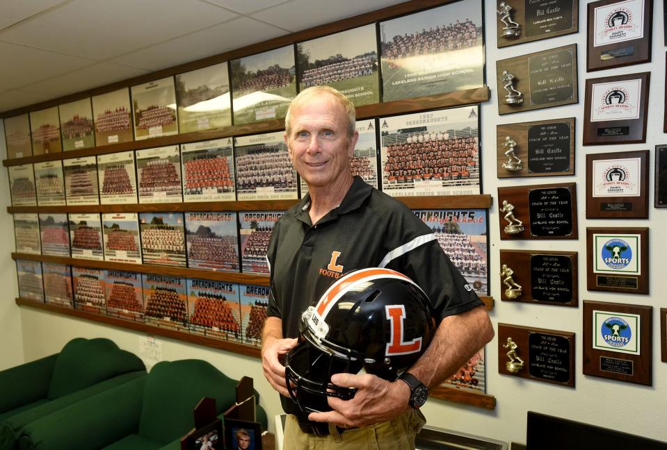 Bill Castle poses in 2016 with the team pictures of many of the teams he has coached during his 47-year tenure as Lakeland's head coach.