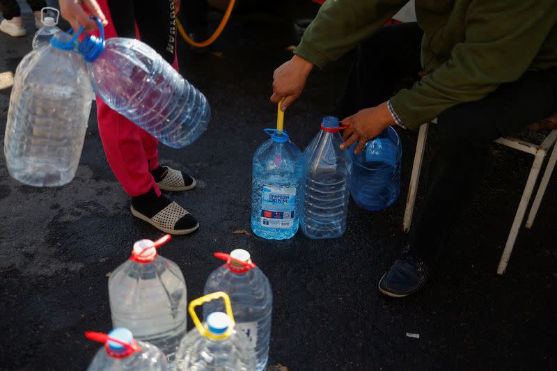 Local people fill up bottles with fresh drinking water in Mykolaiv