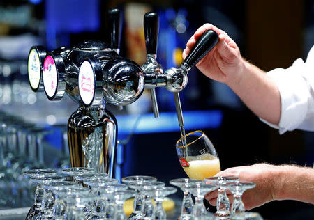 A waiter serves a glass of beer ahead of an Anheuser-Busch InBev shareholders meeting in Brussels, Belgium April 30, 2014. REUTERS/Yves Herman/File photo