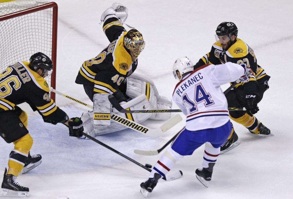 Boston Bruins goalie Tuukka Rask (40) makes the save on a shot by Montreal Canadiens center Tomas Plekanec (14) during the first period of Game 5 in the second-round of the Stanley Cup hockey playoff series in Boston, Saturday, May 10, 2014. Bruins defenseman Kevan Miller, left, and center Patrice Bergeron, right, move in. (AP Photo/Charles Krupa)
