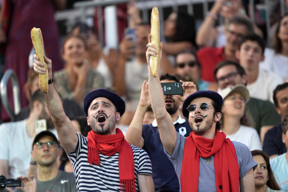 Thomas Zellner, left and Thibault Vinson celebrate being Parisian while cheering for France's Lezana Placette and Alexia Richard in a beach volleyball match against Germany at the 2024 Summer Olympics, Monday, July 29, 2024, in Paris, France. (AP Photo/Robert F. Bukaty)