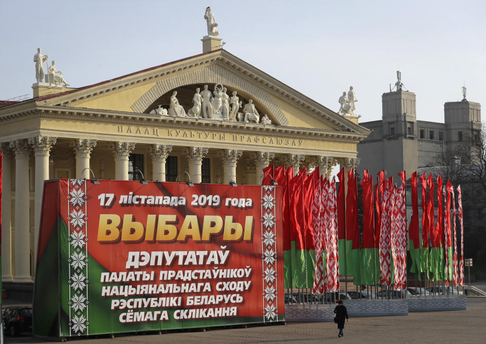 FILE - A woman walks past a huge election banner and Belarus national flags in Minsk, Belarus, on Nov. 13, 2019. Belarusians will cast ballots Sunday in tightly controlled parliamentary and local elections that are set to cement an authoritarian leader's rule, despite calls for a boycott by an opposition leader who described the balloting as a "senseless farce." (AP Photo, File)