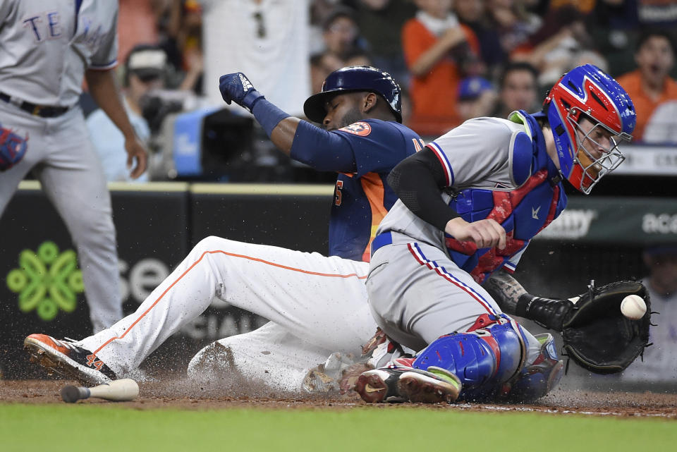 Houston Astros' Yordan Alvarez, left, slides safely past Texas Rangers catcher Jonah Heim to score on Kyle Tucker's RBI single during the sixth inning of a baseball game, Sunday, July 25, 2021, in Houston. (AP Photo/Eric Christian Smith)