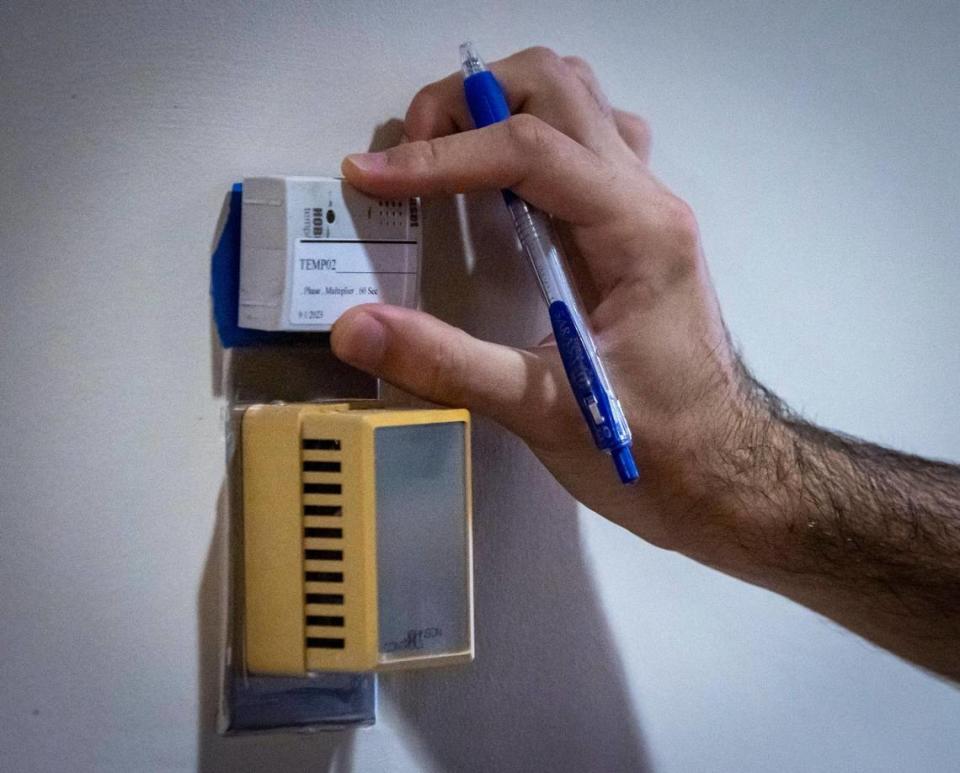 A member of the University of Miami Industrial Assessment Center team places a sensor on top of a thermostat inside 550 Biltmore Way in Coral Gables.