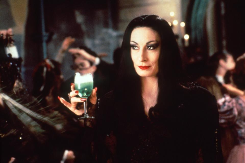 Curious what's in Morticia's glass? Our Poisoned Apple Martini, complete with smoking dry ice, is the perfect way to channel Addams vibes. (Photo: Everett Collection)