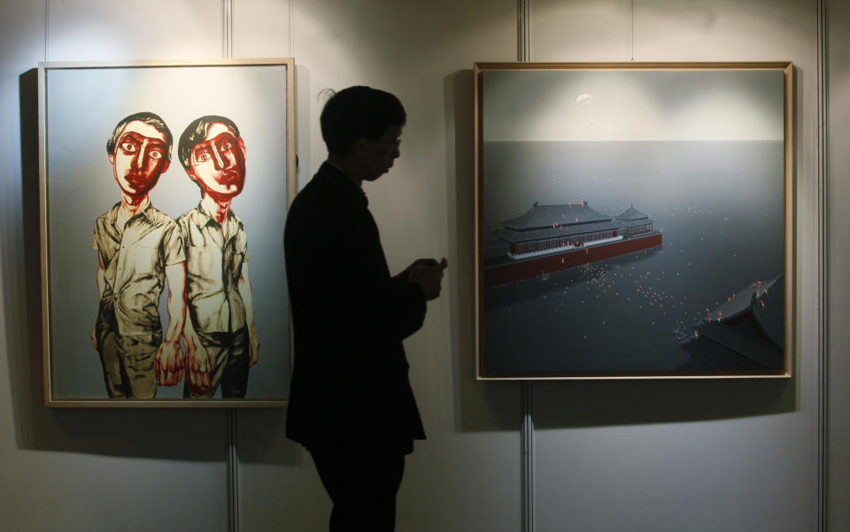 A man walks past paintings titled "Flooding the Forbidden City No.10", right, by Chinese artist Chen Lianqing and "Two Men (from Mask Series)" by Chinese artist Zeng Fanzhi at the Seoul Auction in Hong Kong Tuesday, April 3, 2012. Auctioneers in Hong Kong have sold 10 paintings seized from a South Korean bank that collapsed last year amid a corruption scandal to raise $2.4 million to help repay depositors. The paintings included works by noted Chinese artists Zeng and Zhang Xiaogang and American Julian Schnabel. (AP Photo/Kin Cheung)