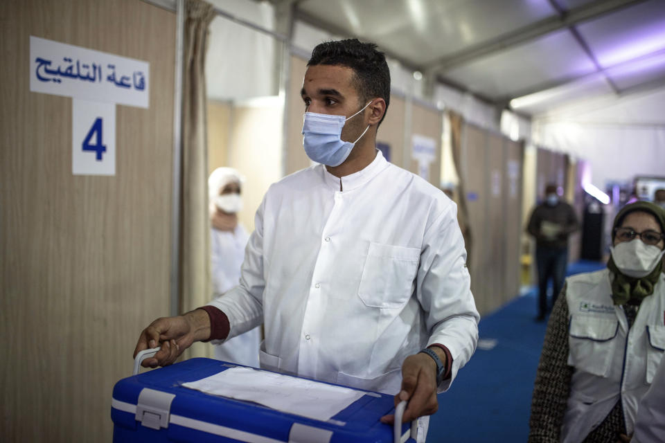 A health worker carries doses of the AstraZeneca-Oxford COVID-19 vaccine on the first day of vaccination campaign, in Rabat, Morocco, Friday, Jan. 29, 2021. Morocco's King Mohammed VI received a shot against the coronavirus Thursday to officially kick off his country's COVID-19 vaccination campaign, which initially will primarily target health care workers, security forces and people over age 75, according to Moroccan authorities. (AP Photo/Mosa'ab Elshamy)