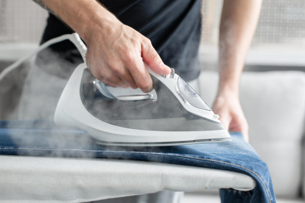 A guy ironing clothes before going outside.