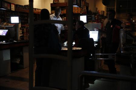 People try to make payment at a supermarket that is running on backup generators after a blackout in Caracas December 2, 2013. REUTERS/Carlos Garcia Rawlins