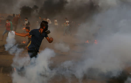 A Palestinian returns a tear gas canister during a protest calling for lifting the Israeli blockade on Gaza and demanding the right to return to their homeland, at the Israel-Gaza border fence in the southern Gaza Strip October 5, 2018. REUTERS/Ibraheem Abu Mustafa