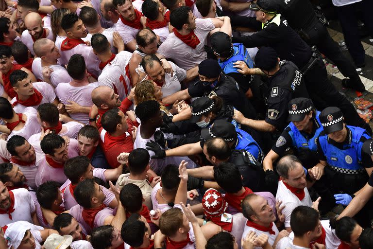 Los agentes de policía intentan controlar a la multitud de juerguistas en la plaza del ayuntamiento esperando el lanzamiento del cohete 'Chupinazo', para marcar la apertura oficial de las fiestas de San Fermín 2022