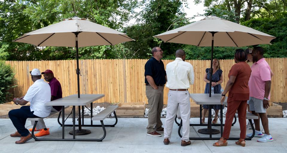 Attendees sit at tables in the backyard at a celebration for the new The Original Project Team sustainability hub Friday, July 1, 2022, at 2854 Douglass Avenue in Orange Mound. The location will feature food distribution, garden and a place to educate on home gardening.