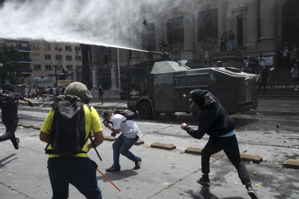 Demonstrators pelt a police water cannon with rocks during a protest in Santiago, Chile, Wednesday, Oct. 23, 2019. Rioting, arson attacks and violent clashes wracked Chile as the government raised the death toll to 15 in an upheaval that has almost paralyzed the South American country long seen as the region's oasis of stability. (AP Photo/Rodrigo Abd)