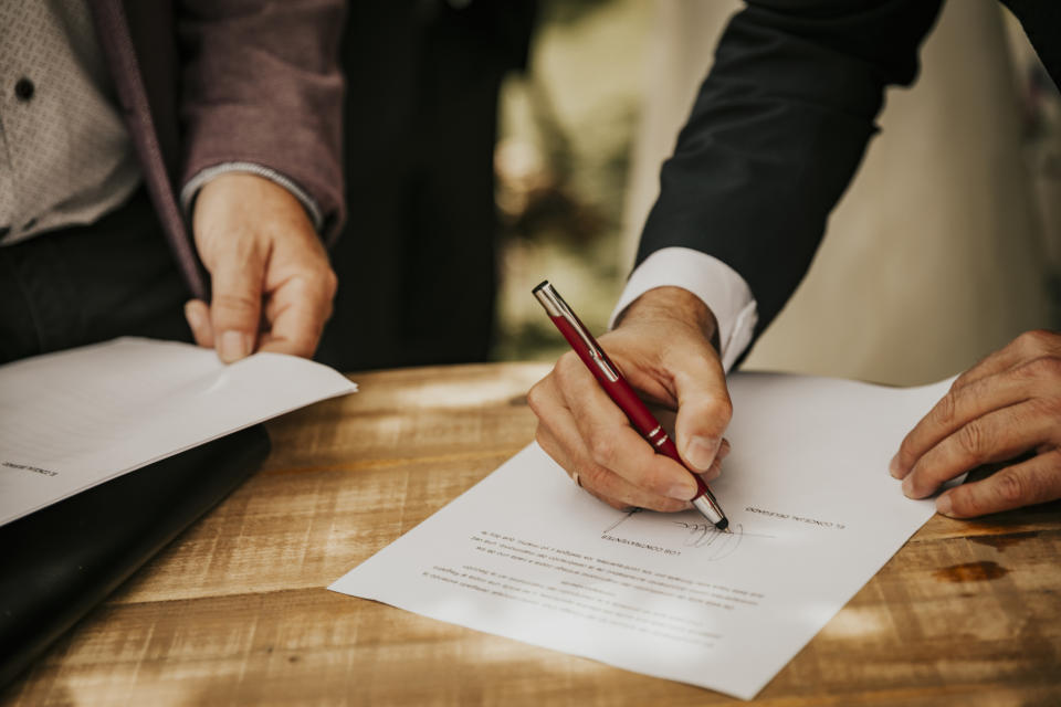 Two individuals signing a document, potentially a relationship contract or agreement