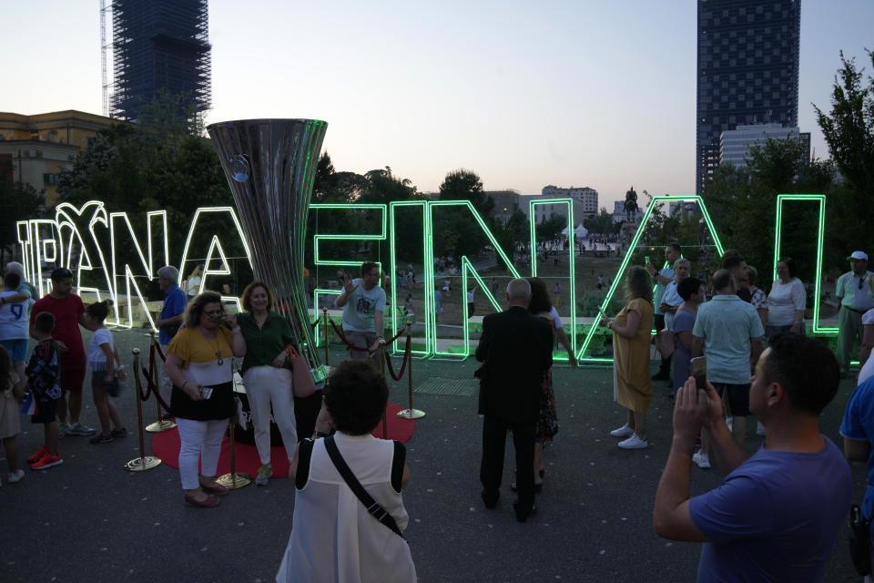 People pose for pictures next to a copy of the Conference League trophy in downtown of Tirana, Albania, Tuesday, May 24, 2022. Feyenoord will play Roma Wednesday in the Europa Conference League Final. (AP Photo/Antonio Calanni)