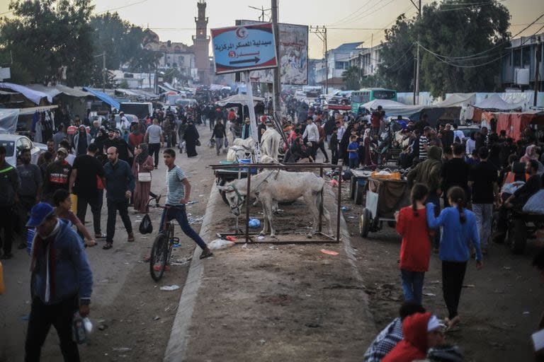 Palestinos caminan por la calle cerca del Hospital Nasser y de las escuelas administradas por la Agencia de Obras Públicas y Socorro de las Naciones Unidas para los Refugiados de Palestina en el Cercano Oriente (OOPS), en la ciudad de Khan Yunis, en medio de batallas en curso