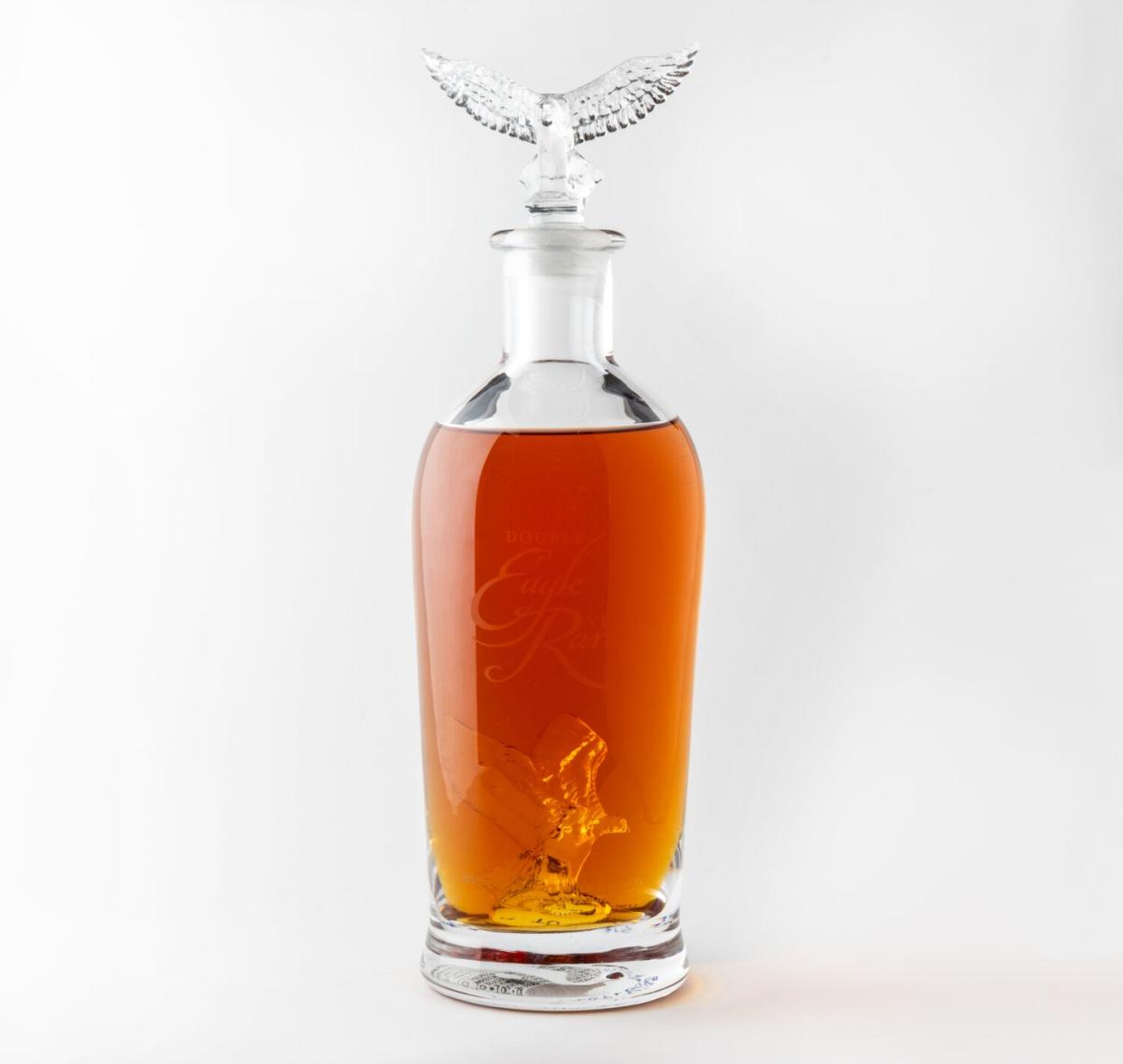 A glass bottle filled with brown-colored bourbon and topped with an spread-wing eagle stopper.