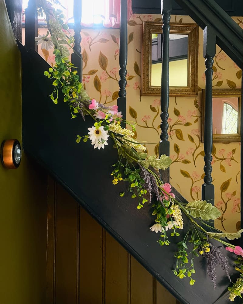 Floral garland trailing up stairs in entry of home.