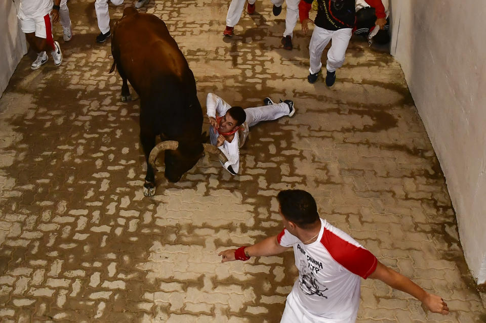 A runner falls as a fighting bull charges past during the running of the bulls at the San Fermin Festival in Pamplona, northern Spain, Tuesday, July 12, 2022. Revellers from around the world flock to the city every year for nine days of uninterrupted partying in Pamplona's famed running of the bulls festival, which was suspended for the past two years because of the coronavirus pandemic. (AP Photo/Alvaro Barrientos)