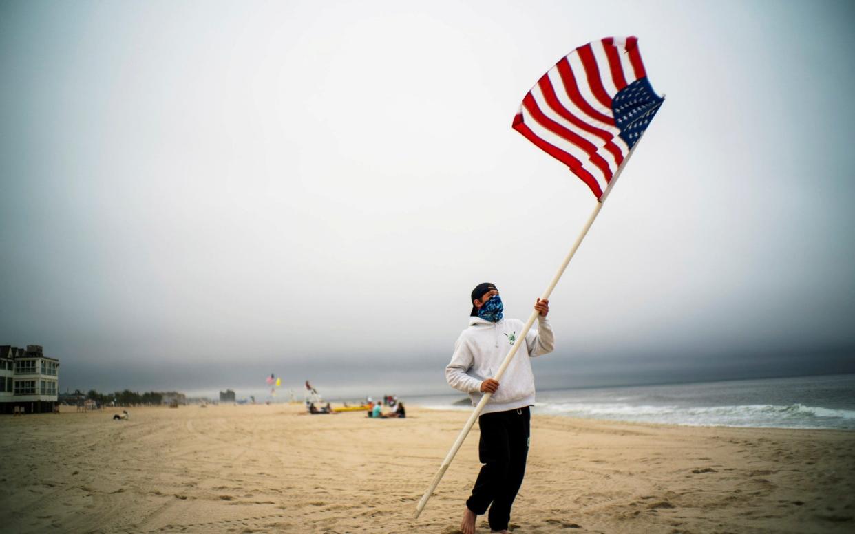 A beach guard removes the US flag after a day of duty at Long Branch beach after New Jersey beaches were opened  - Reuters