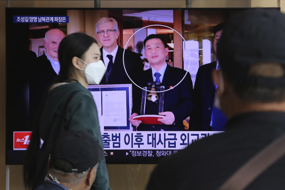 People watch a TV showing an image of Jo Song Gil, the North Korea's former ambassador to Italy, right, during a news program at the Seoul Railway Station in Seoul, South Korea, Wednesday, Oct. 7, 2020. Jo who had vanished in Italy in late 2018, currently lives in South Korea under government protection, a lawmaker said Wednesday. The Korean letters read: "Ambassador level diplomat." (AP Photo/Ahn Young-joon)