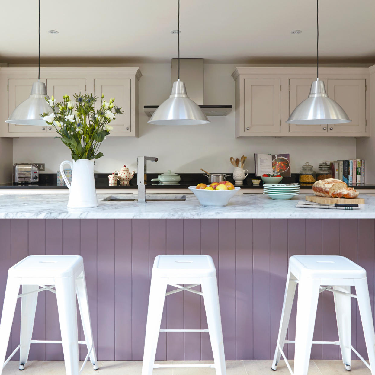  Modern hwite kitchen, large lilac breakfast bar with high bar stools, low hanging pendant lights. 