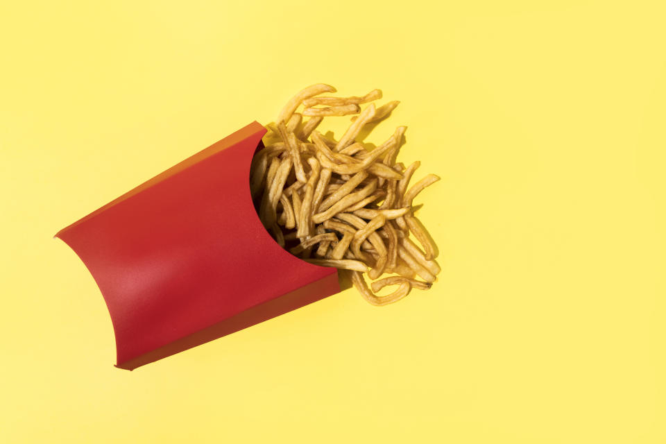 Spilled carton of french fries on a plain surface