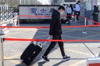 Employee wearing a face mask pulls luggage as he enters Foxconn Science and Technology Industrial Park, following an outbreak of the novel coronavirus in the country, in Taiyuan, Shanxi