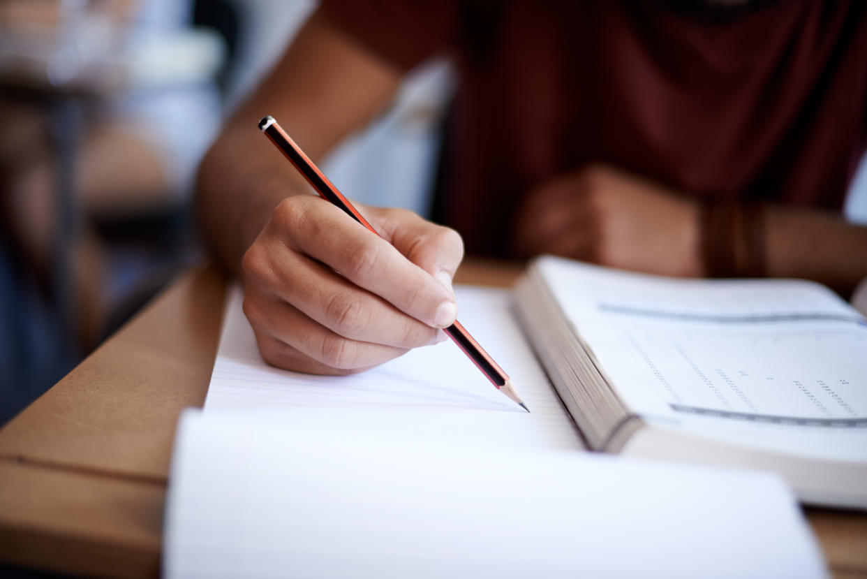 A young man writes on a notepad.