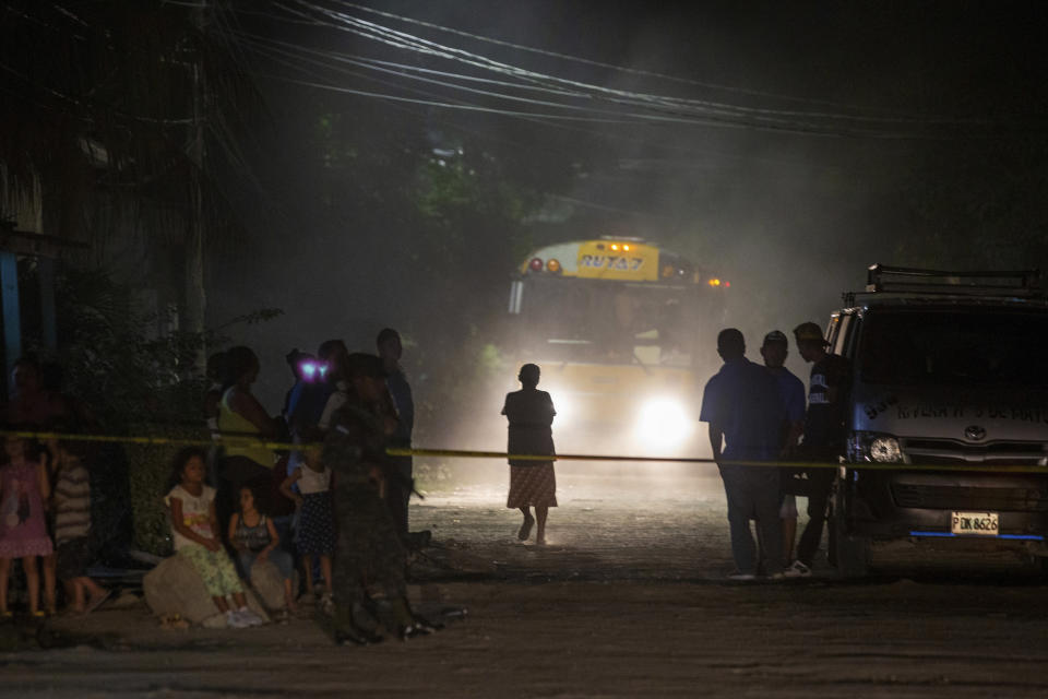 Neighbors watch as police and forensic workers inspect a body at a crime scene in the Rivera Hernandez neighborhood of San Pedro Sula, Honduras, on Nov. 30, 2019. (AP Photo/Moises Castillo)