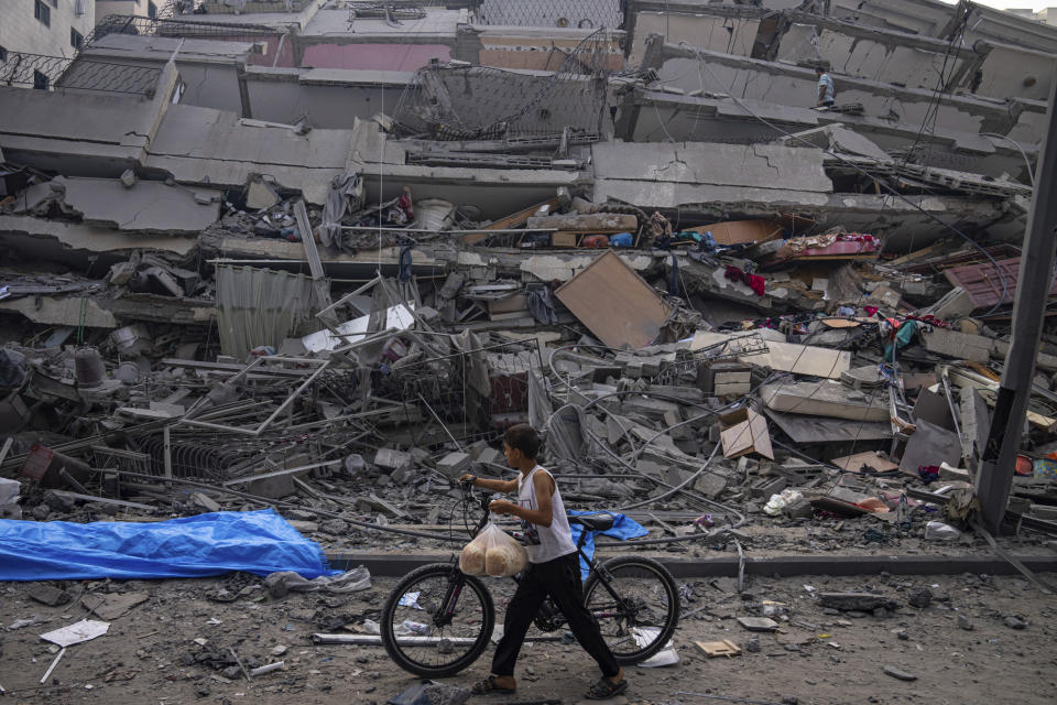 FILE - A Palestinian child walks with a bicycle by the rubble of a building after it was hit by an Israeli airstrike, in Gaza City, Oct. 8, 2023. (AP Photo/Fatima Shbair, File)