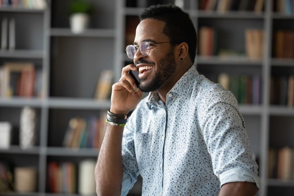 An investor smiles while talking on the phone in a living room.