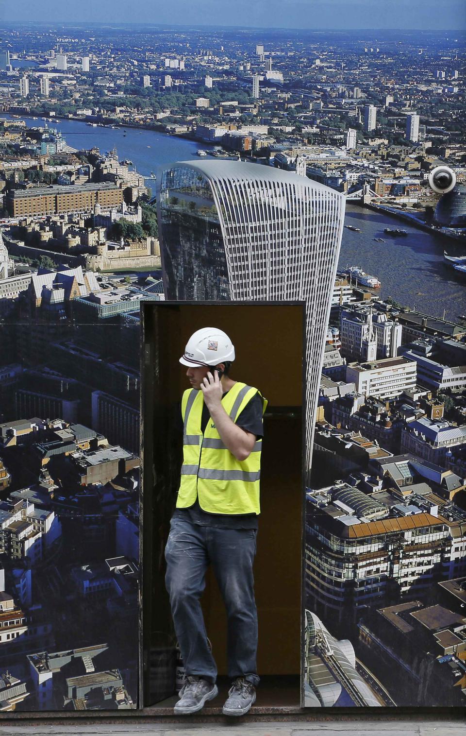 A worker walks out of a hoarding showing the Walkie Talkie tower in London
