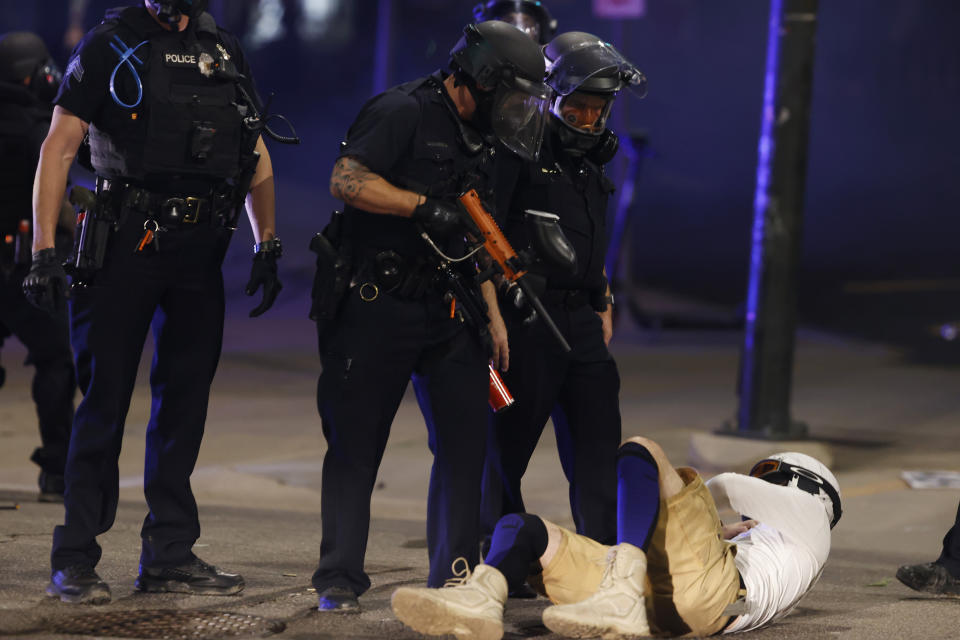 Denver Police Department officers stand over a man who fell to the street after they used tear gas and rubber bullets to disperse a protest outside the State Capitol over the death of George Floyd, a handcuffed black man who died in police custody in Minneapolis, late Thursday, May 28, 2020, in Denver. (AP Photo/David Zalubowski)