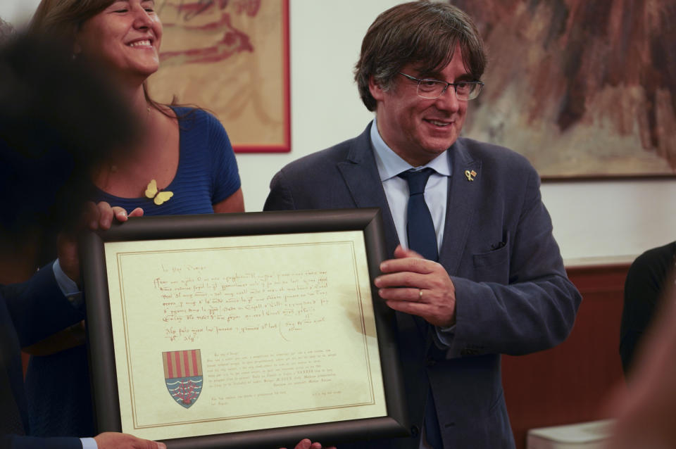 Catalan separatist leader Carles Puigdemont, right, flanked by Speaker of the Catalan Parliament Laura Borras exchanges gifts with Mayor of Alghero Mario Conoci in Alghero, Sardinia, Italy, Saturday, Sept. 25, 2021. Puigdemont was visiting the city hall after he took a leisurely walk in the Sardinian city, waving to supporters, a day after a judge freed him from jail pending a hearing on his extradition to Spain, where the political firebrand is wanted for sedition. (AP Photo/Andrea Rosa)