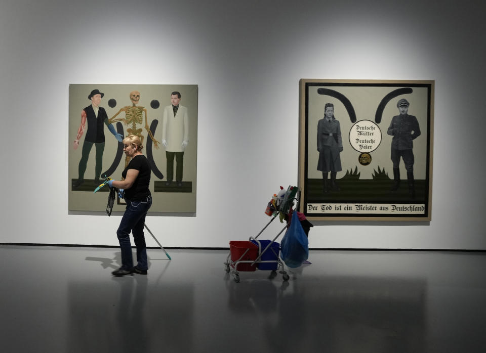 A worker cleans near an exhibit by Danish conceptual artist Kristian von Hornsleth at the Ujazdowski Castle Center for Contemporary Art in Warsaw, Poland, Wednesday Aug. 25, 2021. The exhibition which opens Friday at the Polish state museum features the works of provocative artists in what organizers describe as a celebration of free speech, and a challenge to political correctness and "cancel culture" on the political left. Some critics, however, accuse the organizers of the show titled "Political Art" of giving a platform to anti-Semitic, racist and Islamophobic messages. Words in the right artwork read: *German Mothers, German Fathers, Death Is A Master From Germany'. (AP Photo/Czarek Sokolowski)